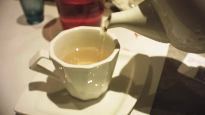 茶壶倒茶动画动作在高档餐厅的白色桌子上摆放着由中国制成的白色杯子，灯光和氛围