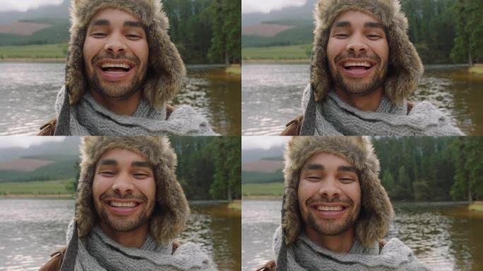 画像年轻男子笑着感觉快乐戴着皮帽在户外的自然湖边