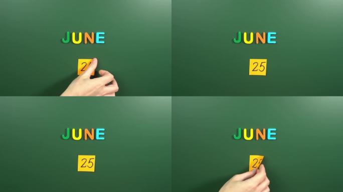 6月25日日历日用手在学校董事会上贴一张贴纸。25 6月日期。6月第二十五天。第25个日期编号。25