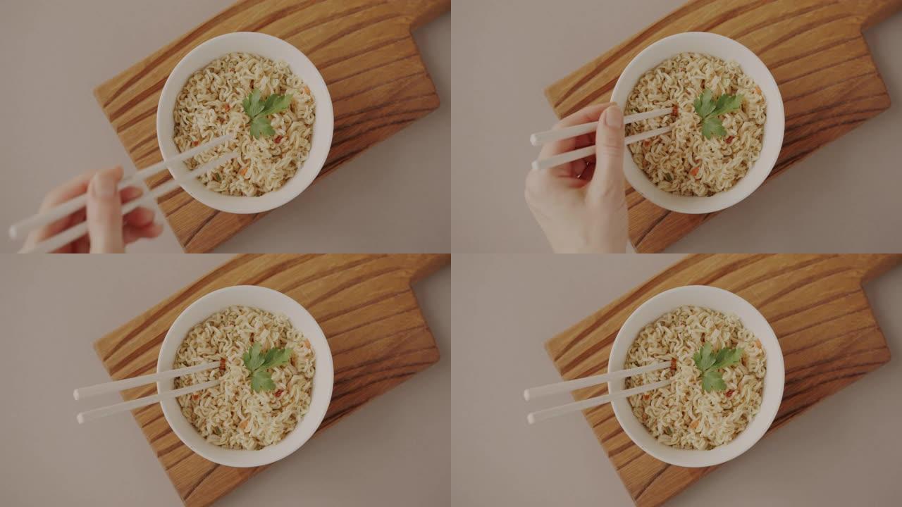 一碗方便面的特写镜头和手把筷子放在盘子里准备吃的