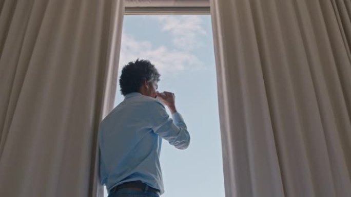 年轻人在酒店房间里喝咖啡，看着窗外，计划着欣赏海洋的景色