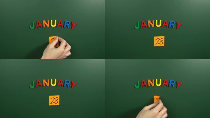 1月28日日历日用手在学校董事会上贴一张贴纸。28 1月日期。1月第二十八天。第28个日期号。28天
