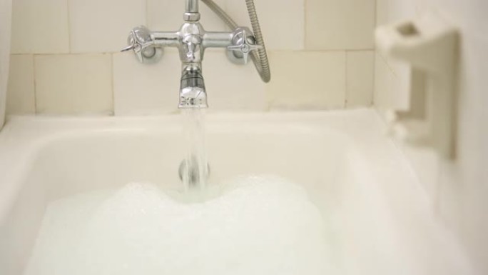 家庭浴室中的水、水龙头和泡泡浴，用于清洁、放松和洗涤，以实现自我护理和禅宗。镀铬水龙头，带有流动液体