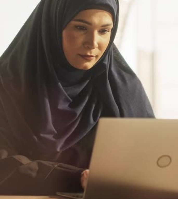 垂直屏幕: 授权一名戴着头巾的穆斯林女商人在公司的笔记本电脑上工作的肖像。阿拉伯金融分析师在新兴的中