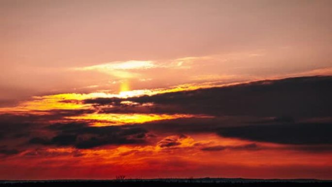 日落通过橙色天空中的云层在地平线上向下移动，延时