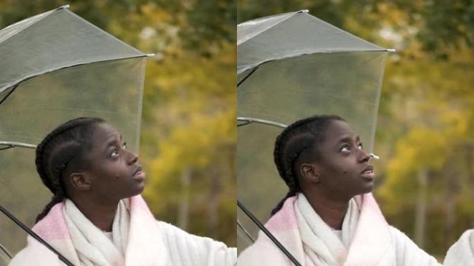 非洲妇女检查秋天是否下雨并关闭雨伞。