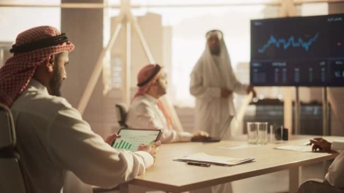 穆斯林商人在与公司合作伙伴的会议上使用平板电脑。经理在会议室听演讲时熟悉财务年度报告