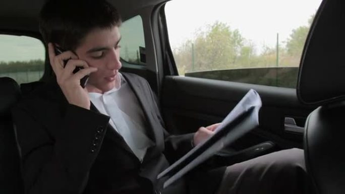 忙碌的商人在汽车上拿着文件和手机