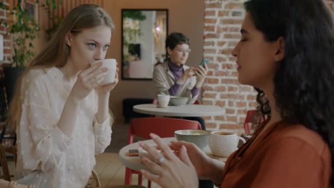 快乐的年轻女性朋友聊天和喝咖啡在咖啡馆玩得开心
