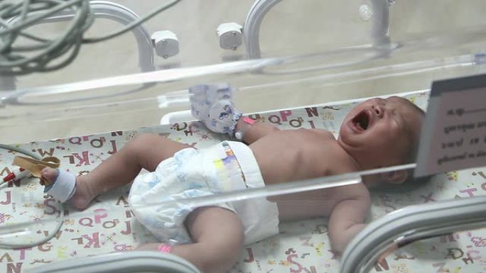 在托儿所的孵化器护理中哭泣的新生婴儿