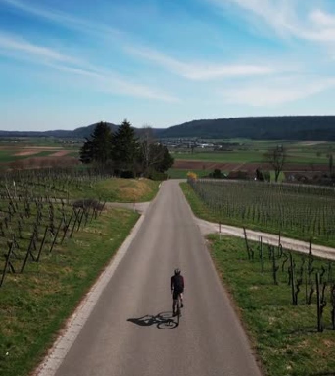 骑自行车的人在自行车上训练，在绿色的山丘上爬坡，垂直视频