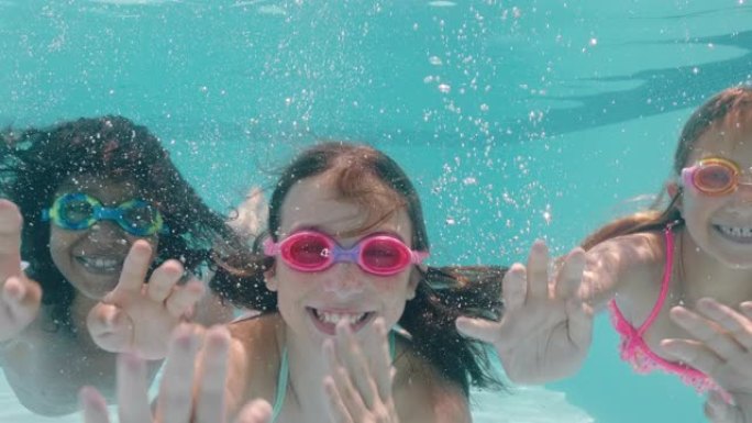 快乐的孩子在游泳池水下游泳微笑挥动双手孩子们享受暑假一起漂浮在清澈的水中