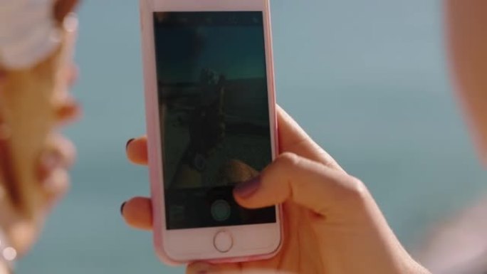 特写手女人用智能手机拍照冰淇淋享受暑假在海滩上吃软食分享经验