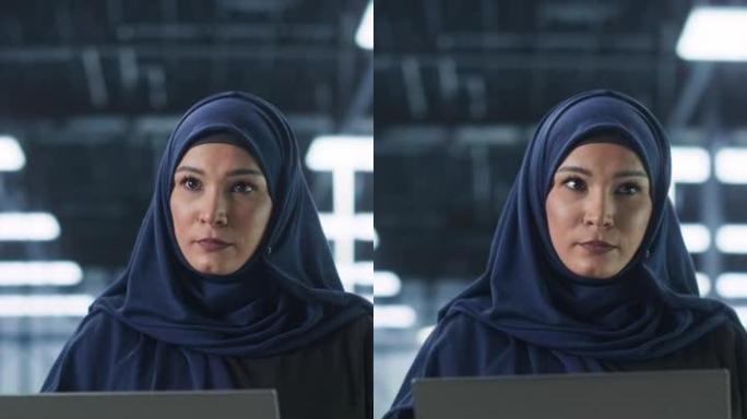 垂直屏幕: 年轻的中东女性IT系统工程师穿着传统的头巾，在现代技术服务器设施中使用笔记本电脑。工作中