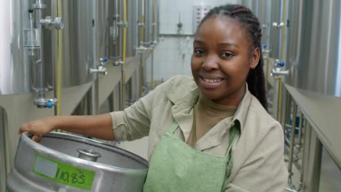 带着啤酒桶微笑的黑人女啤酒厂工人的肖像