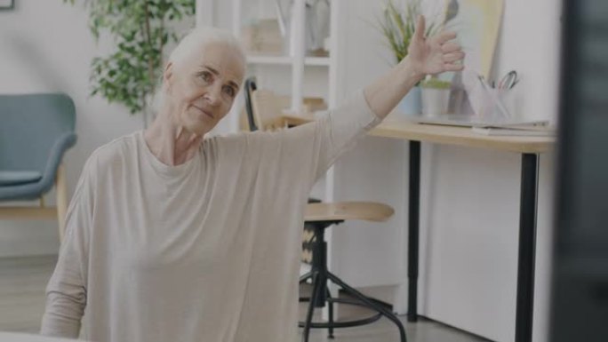退休妇女在电视上观看体育节目并在家中照顾健康的慢动作肖像
