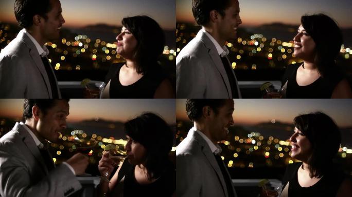 一个男人和女人在黄昏时在屋顶上喝鸡尾酒时聊天和调情
