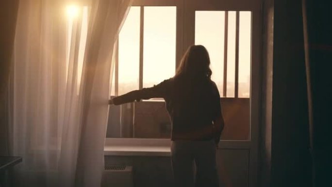 年轻女孩的剪影带着夕阳的光线走近窗户，打开窗帘