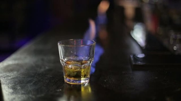 酒吧柜台上带火的威士忌杯