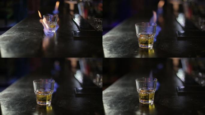 酒吧柜台上带火的威士忌杯
