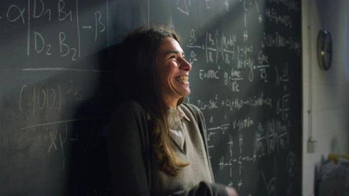 教室里快乐的年轻女老师的肖像躺在黑板上，带着数学公式，微笑着。科学研究人员获得赠款，对新的机会感到兴
