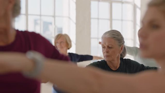 瑜伽课的健康成熟女性练习战士姿势享受早晨体育锻炼工作室