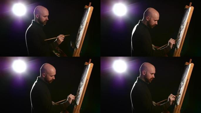 穿着深色毛衣的塔拉特德画家继续用油画绘画，手里拿着调色板在黑色背景上，背光，慢动作