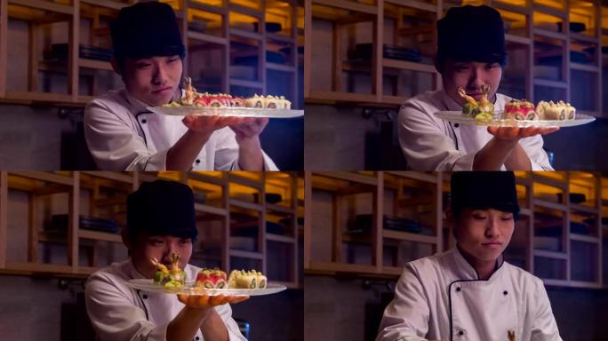 穿着白色制服的微笑亚洲厨师站在寿司店的厨房里，用面包卷翻盘