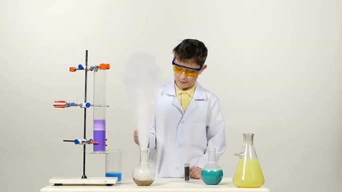 穿着制服的小男孩化学家，防护眼镜成功测试了新配方和奇迹，在白色背景上