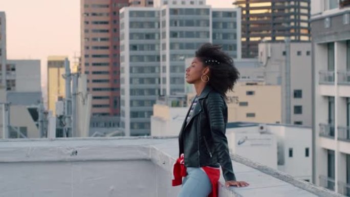 慢镜头，年轻漂亮的非裔美国女性在屋顶放松，自信地享受着迷人的城市生活方式，风在城市背景中吹着头发