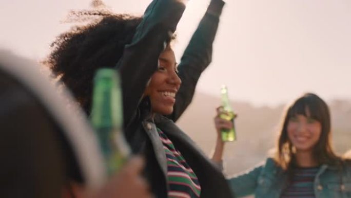 一群多种族的朋友闲逛着年轻的非洲裔美国妇女在日落时分享受屋顶派对喝酒在周末庆祝活动中玩得开心