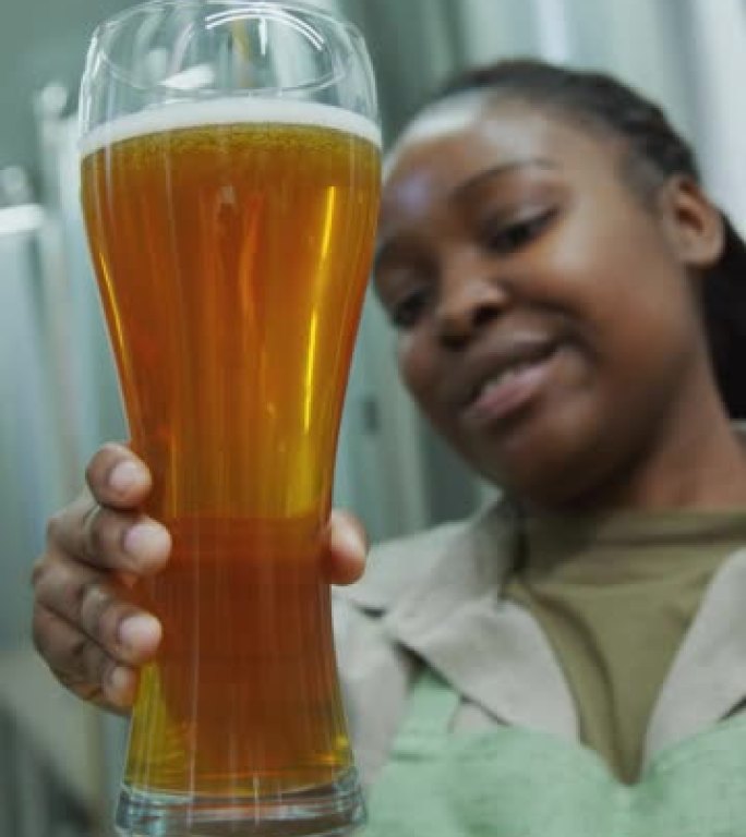 快乐的女性啤酒厂技术专家欣赏新型啤酒