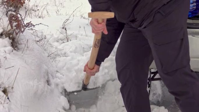 男子在汽车附近用铲子挖雪