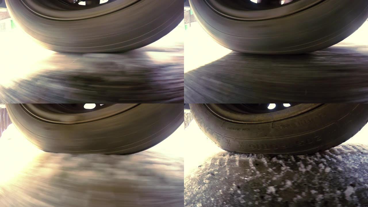特写车轮从汽车视点下旋转。在积雪覆盖的道路上驾驶汽车