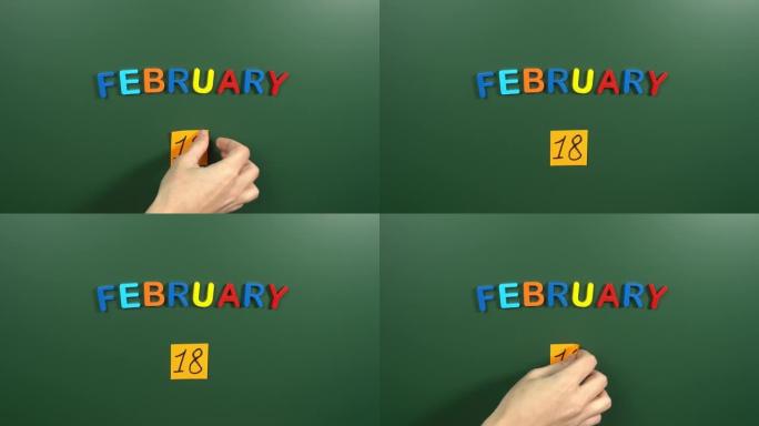 2月18日日历日用手在学校董事会上贴一张贴纸。18 2月日期。2月的第十八天。第18个日期编号。18