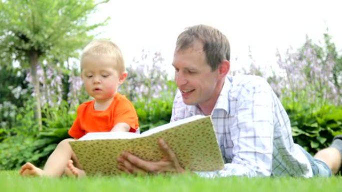 孩子和父亲在花园里看专辑/书