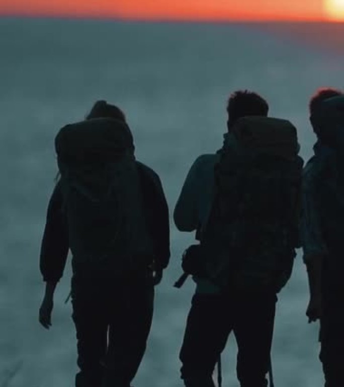 站在日落背景上的一群旅行者。慢动作