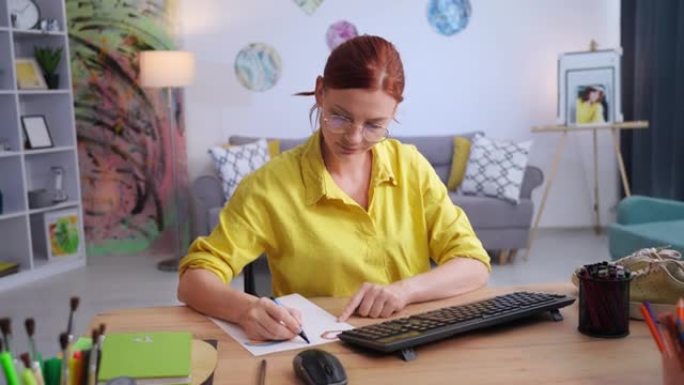 鞋子设计，才华横溢的女人坐在现代公寓的电脑上在纸上画鞋印