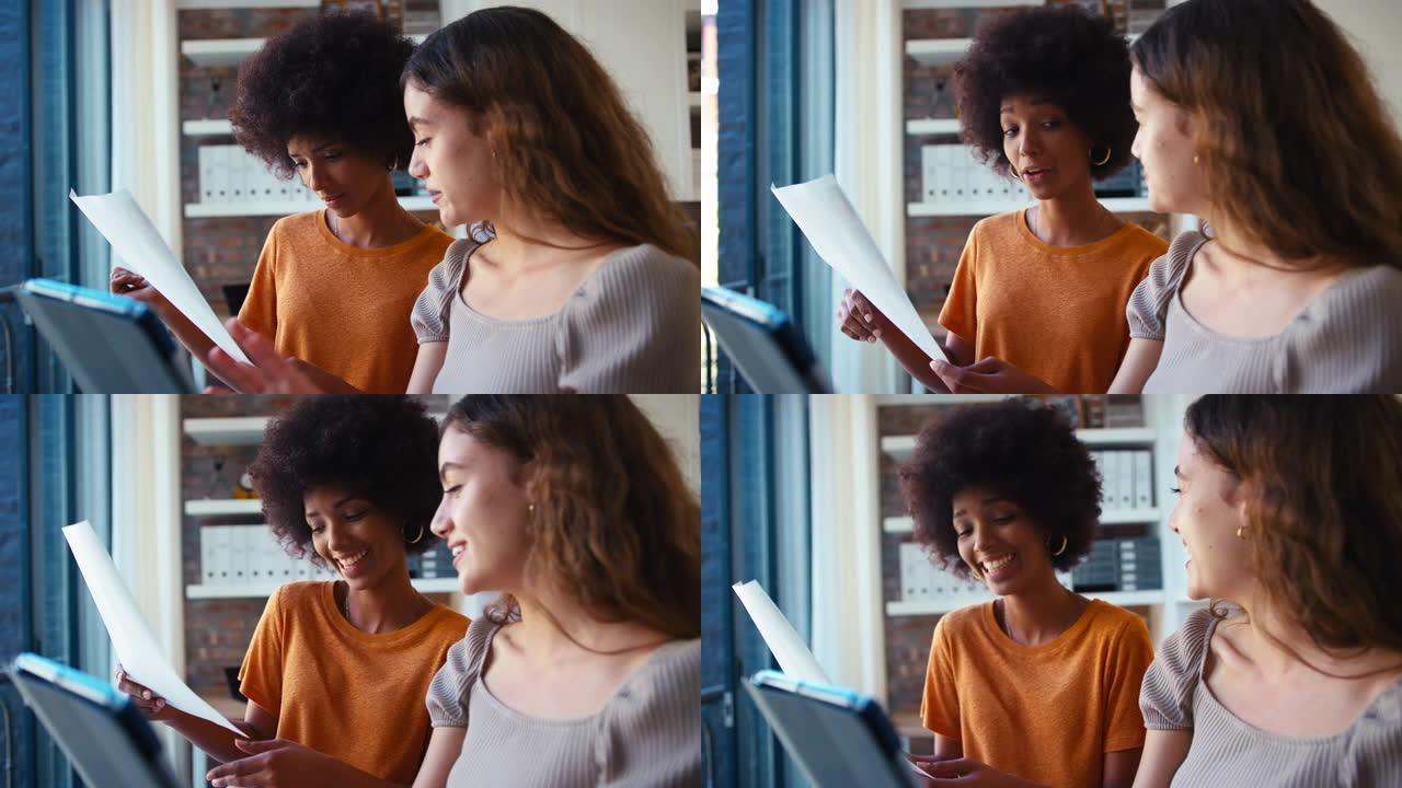 两名年轻的女商人在现代办公室的窗户旁开会，看着数字平板电脑，一起计划-慢动作拍摄