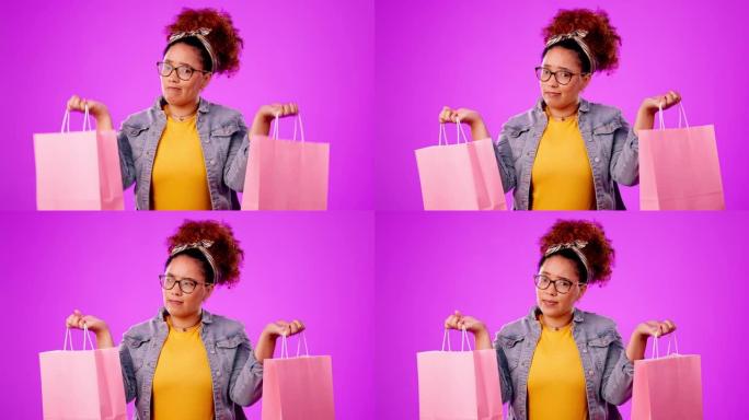 黑人妇女，购物袋和感觉重量，可以在工作室背景下决定或选择礼物。不确定非洲裔美国女性购物者拿着礼物权衡