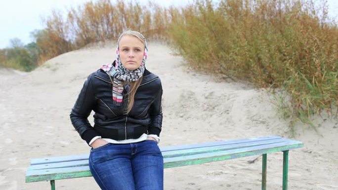 年轻的女孩坐在海边的长椅上。