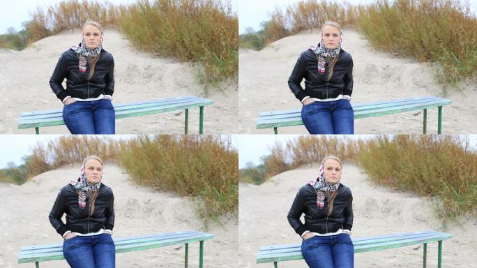 年轻的女孩坐在海边的长椅上。