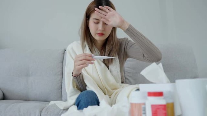 年轻的亚洲妇女在检查体温时发高烧，女性打喷嚏和流鼻涕，季节性流感，过敏，数字温度计，病毒，冠状病毒，