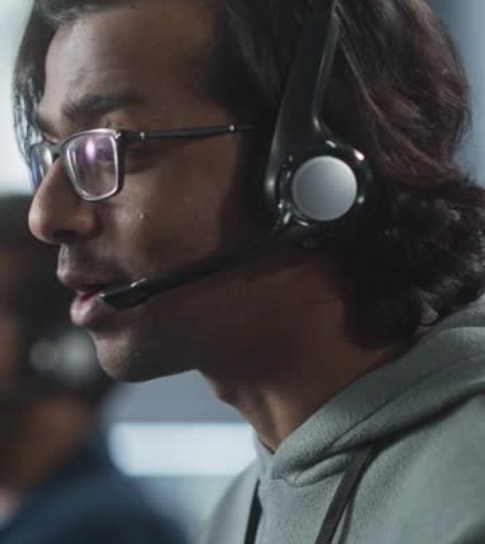 垂直屏幕: 服务台专家在通话中进行对话，为遇到软件问题的客户提供技术支持。印度男子使用耳机与技术团队