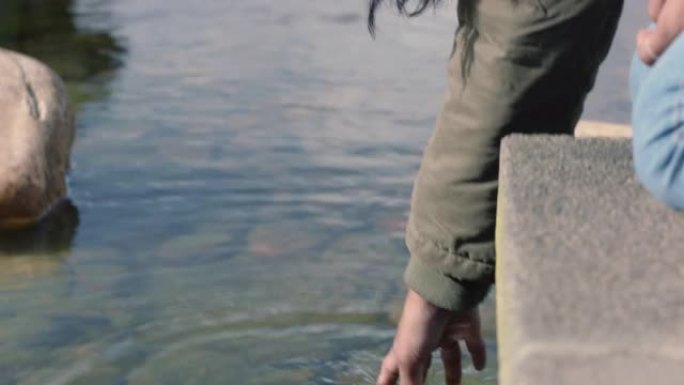 关闭年轻女子泼水在水中嬉戏触摸户外自然公园的新鲜池塘