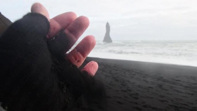 近距离游客参观雷尼斯法拉黑沙滩触摸火山沙。探索冰岛观光概念