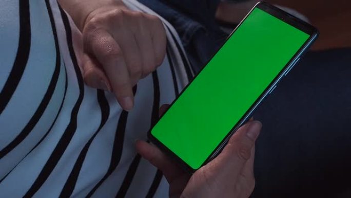 智能手机的绿色屏幕或色度键。女人的手握着手机，点击触摸屏。近距离模拟