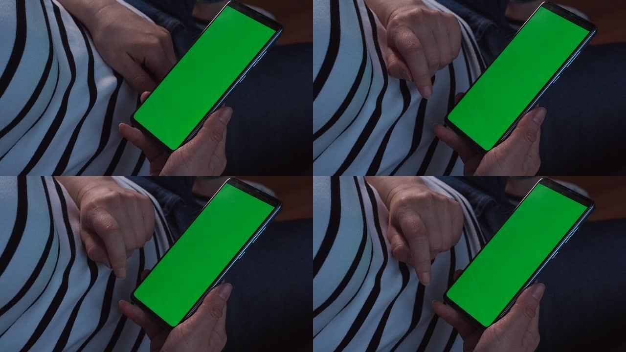智能手机的绿色屏幕或色度键。女人的手握着手机，点击触摸屏。近距离模拟