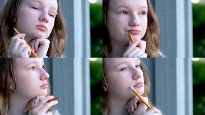 一个年轻的少女女孩手里拿着一支铅笔的悲伤沉思的集中脸认为把它放在她的嘴边的地方文本培训学校课程青春期