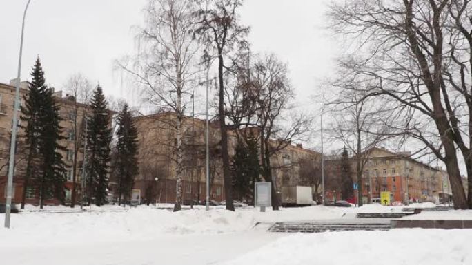 列宁大道在彼得罗扎沃茨克市政厅附近穿过普希金斯卡娅街。冬天的雪堆。车在开，人在走。五层楼的建筑物。云